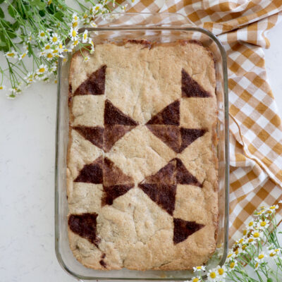 Apple cobbler on gingham checkered tablecloth with a cinnamon sugar quilted pattern on top of the cobbler
