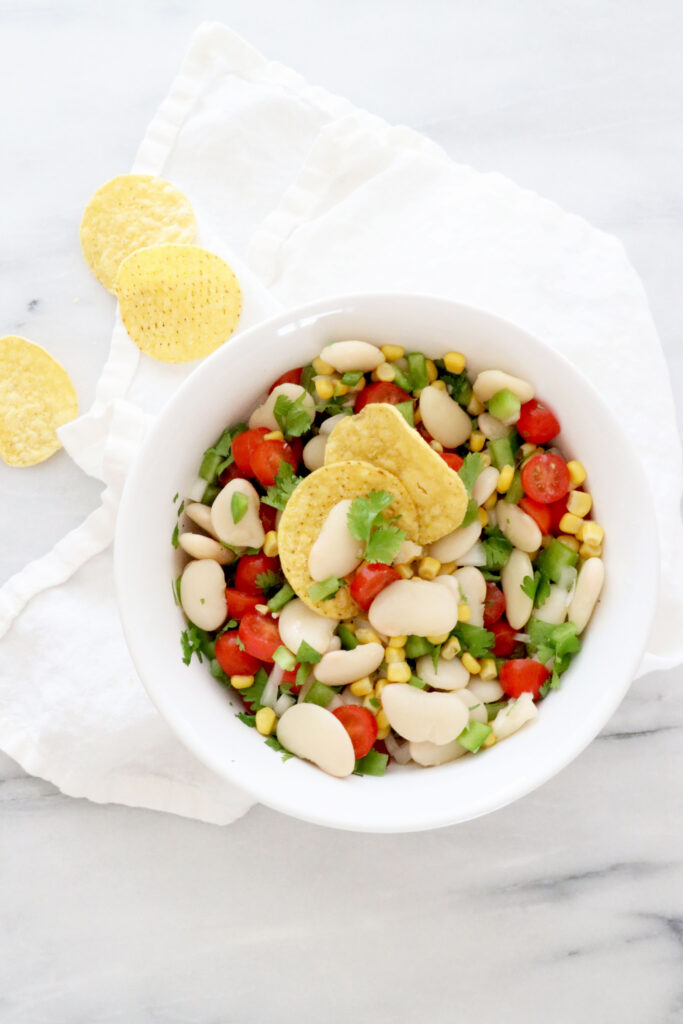 Vertical photo with salsa in center on top of white napkin. A few chips off to the left side.