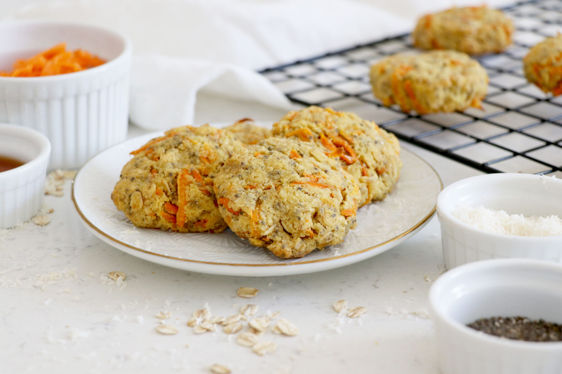 cookies on small plate with chia seeds, coconut, shredded carrots and maple syrup