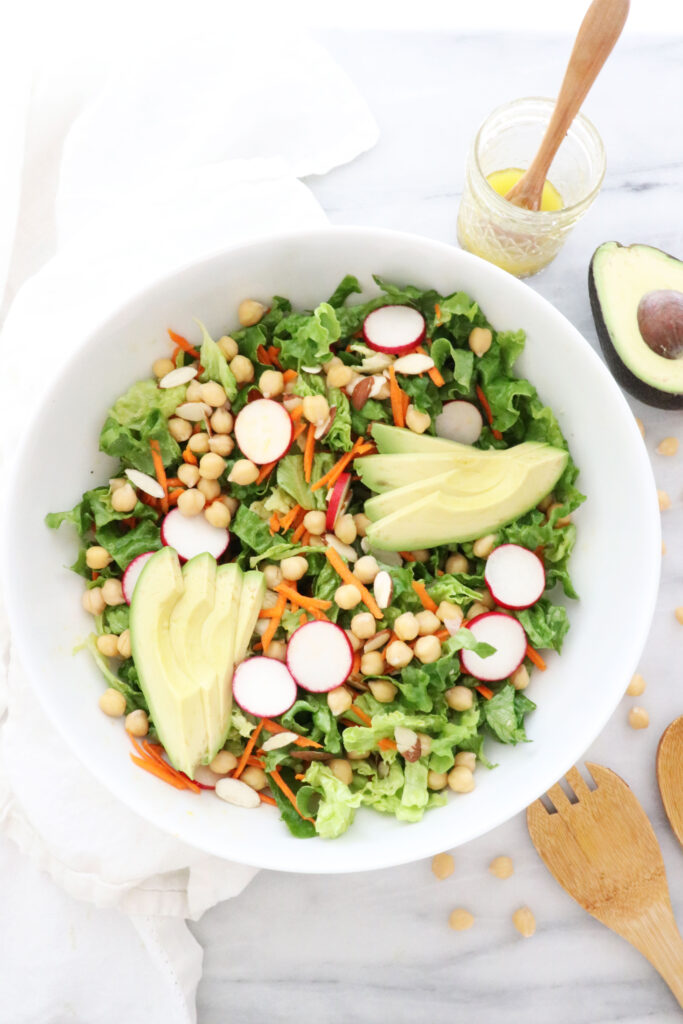 Vertical photo with salad bowl in center. Utensils on the right side