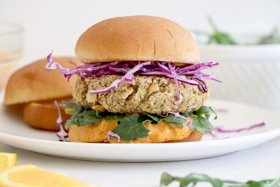 White plate with chickpea burgers. Filled with purple cabbage, sauce and arugula.