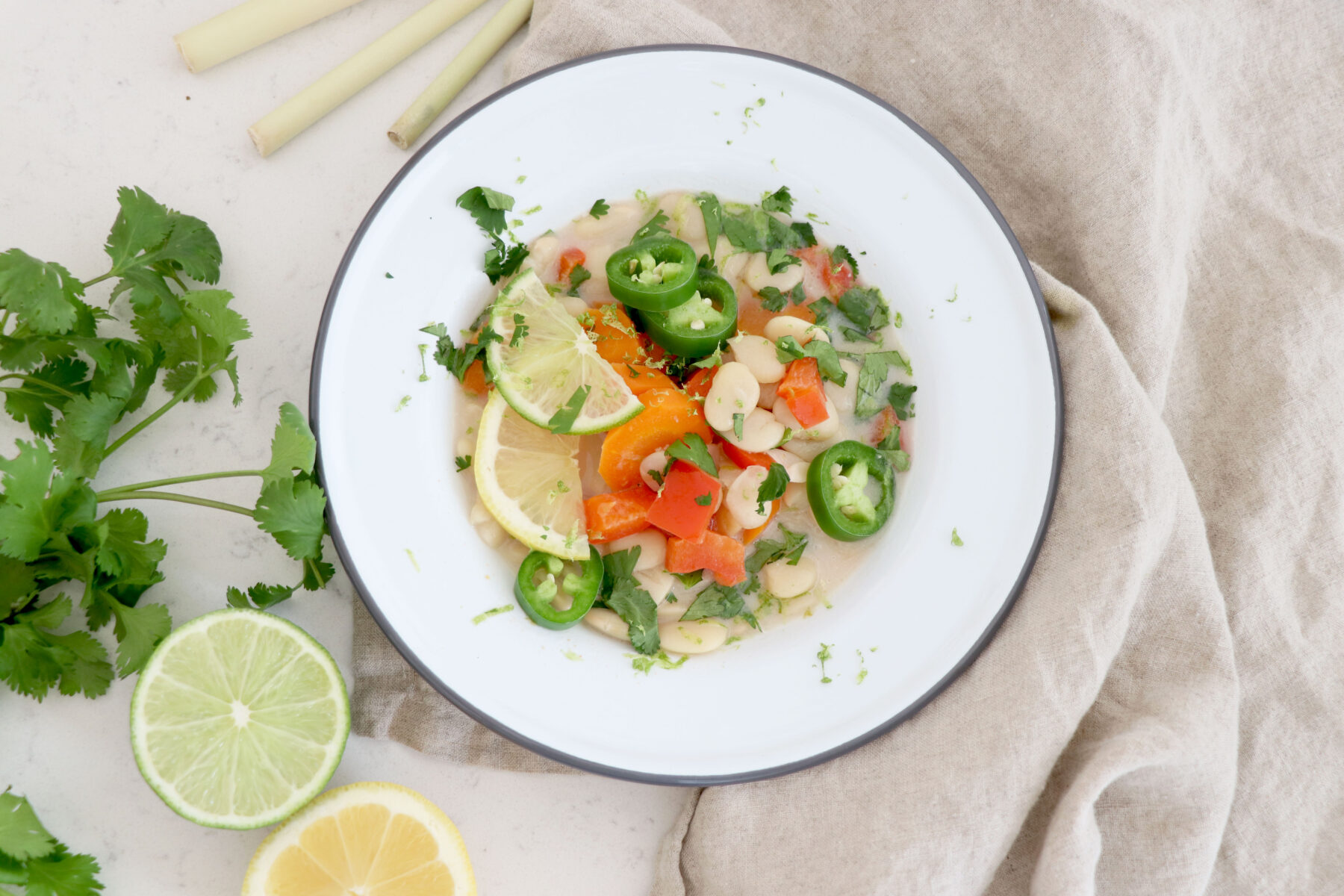 White bowl on beige cloth with lima bean soup and cilantro on left side.