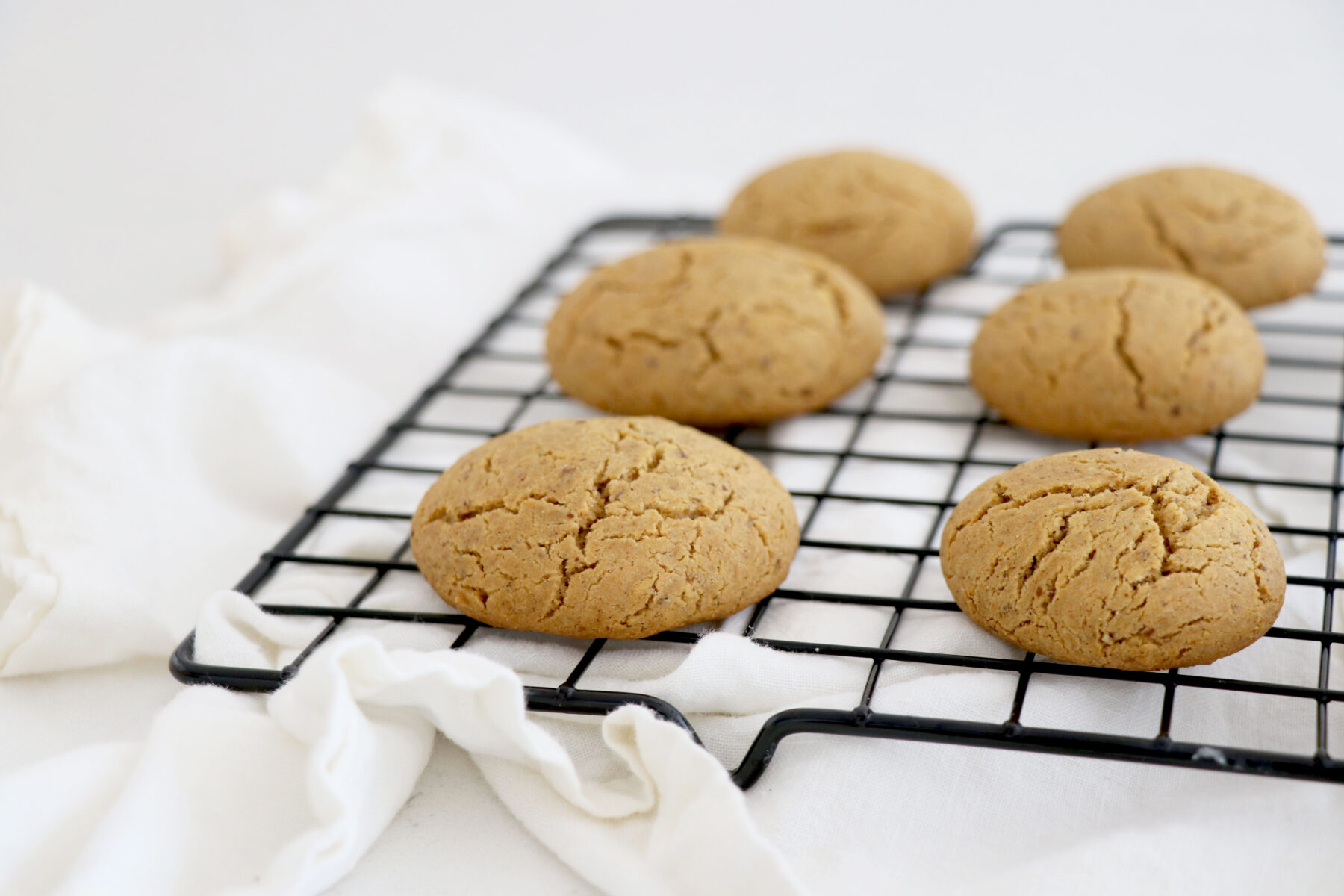 Wire rack with ginger maple cookies on white napkin.