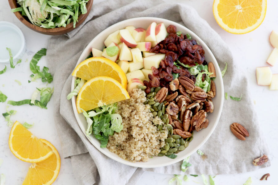 Harvest bowl with greens, pecans, orange slices, quinoa and diced apples.