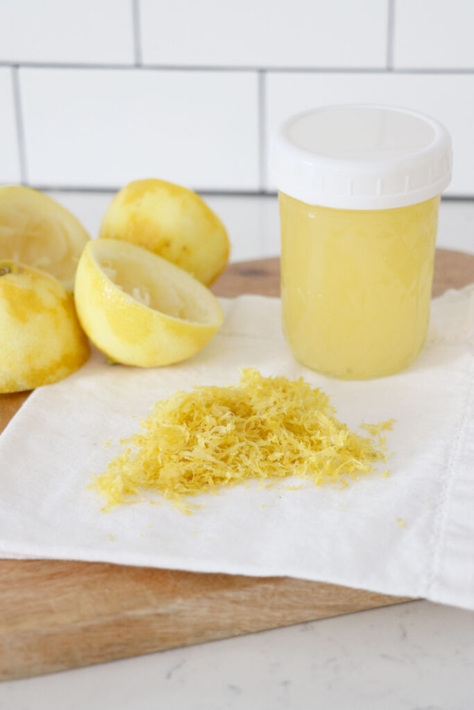 Jar of lemon juice with zest in front on a napkin.