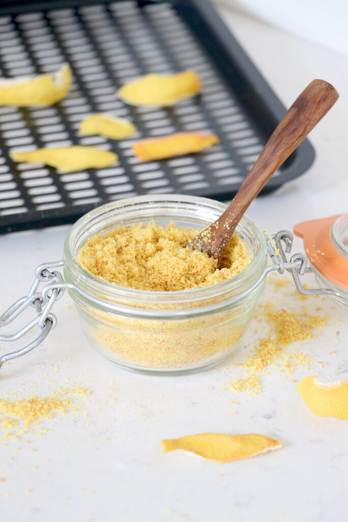 Glass container filled with lemon peel powder.
