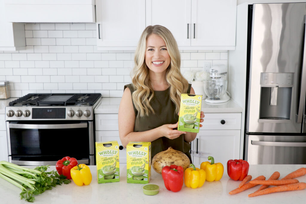 Megan at kitchen island with whole vegetables and Wholly Avocado Minis