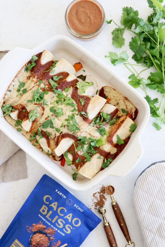 Baking dish with enchiladas surrounded by cacao bliss and cilantro.
