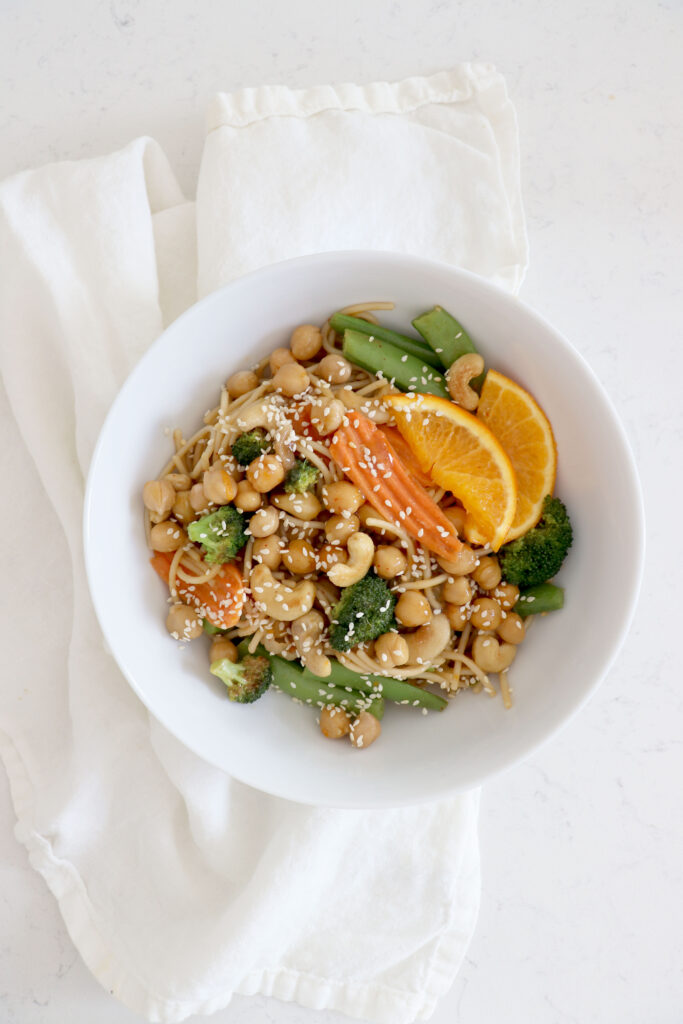 White bowl with chickpea chow mien on white cloth.