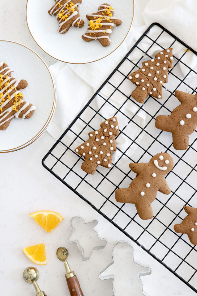 Wire rack with gingerbread cookies and some on white plates in left corner.