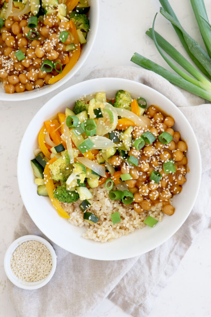 White bowl with chickpea stir fry and green onions on the top right.