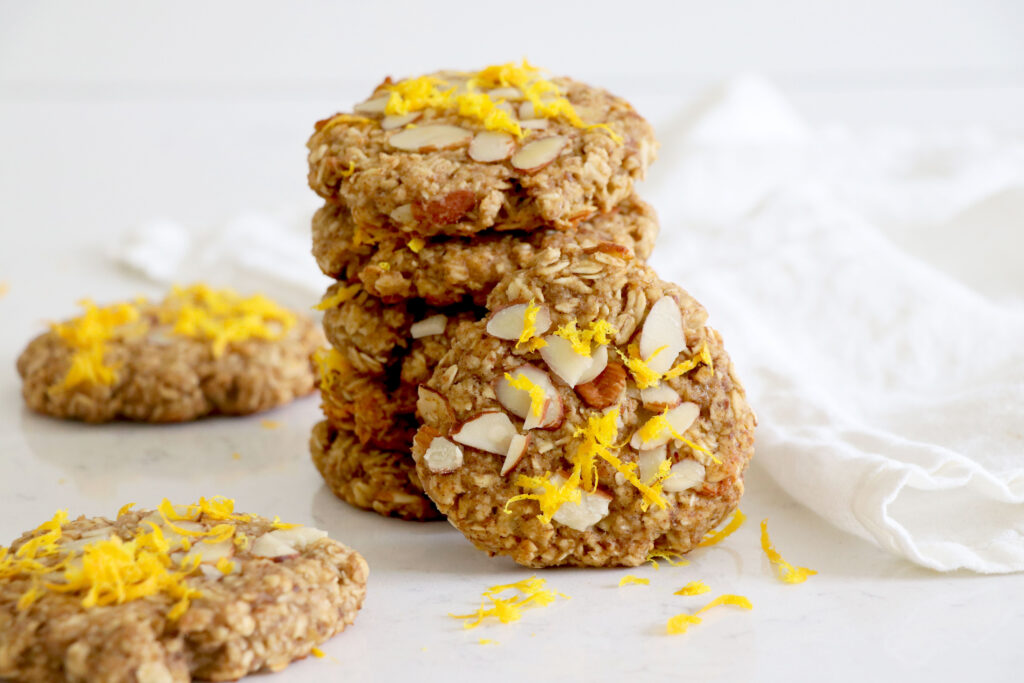 Stack of oatmeal cookies with sliced almonds and lemon zest on top.