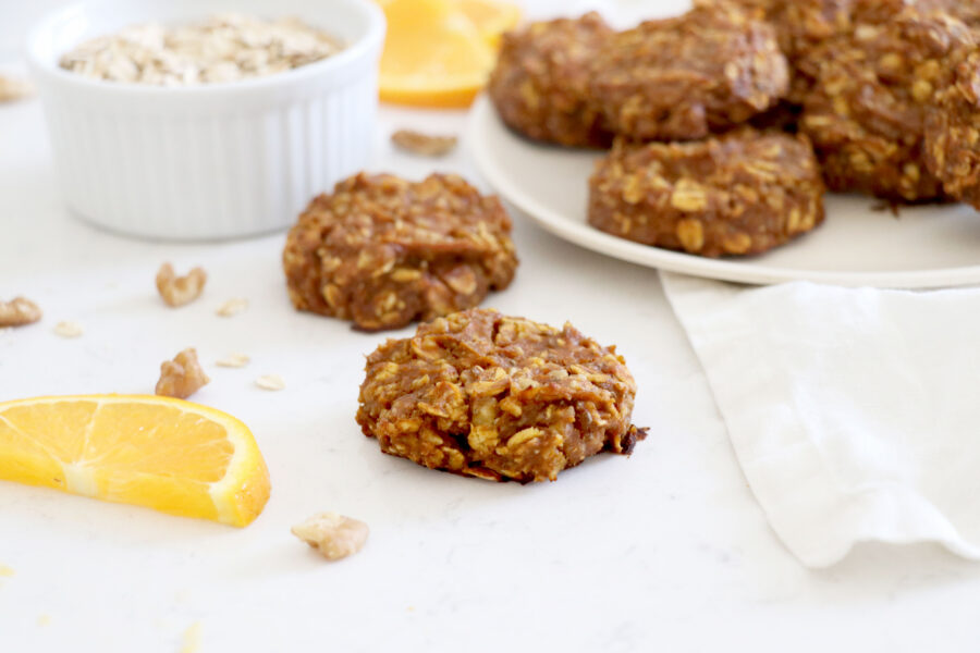 White plate of oatmeal cookies and two in the front.