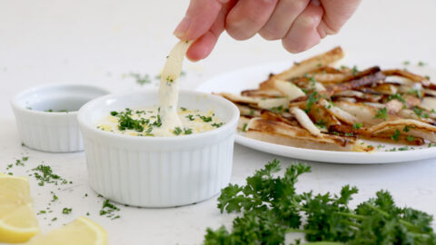 Hand dipping parsnip fries into lemon aioli sauce.