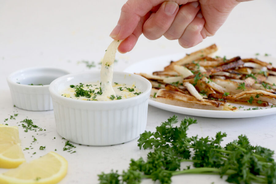 Hand dipping parsnip fries into lemon aioli sauce.