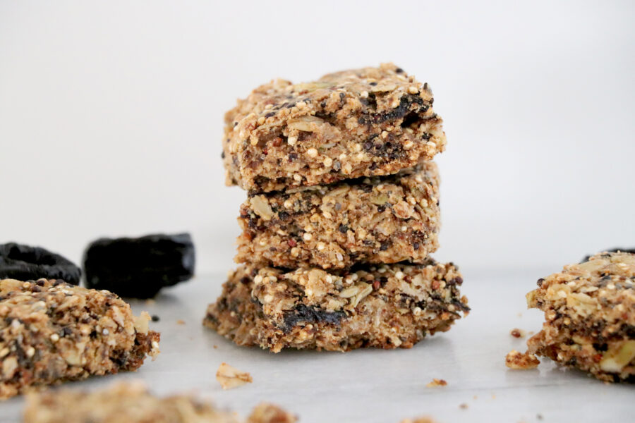 3 breakfast bars stacked on each other with prunes on the side