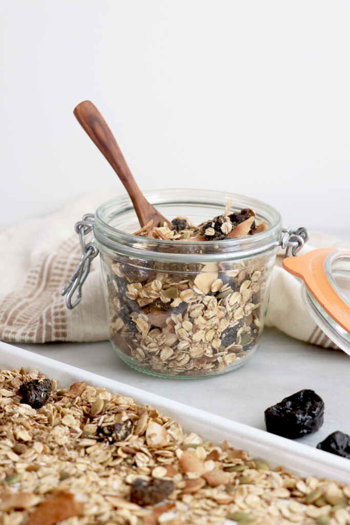 Clear c container with muesli inside and spoon on top.