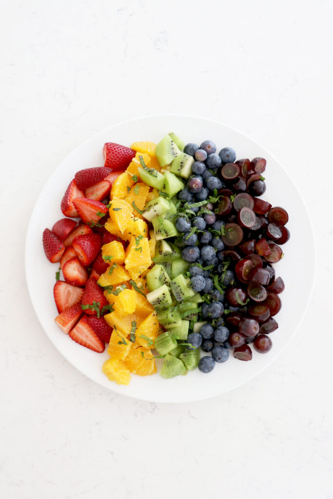 White plate with assorted fruit by color.