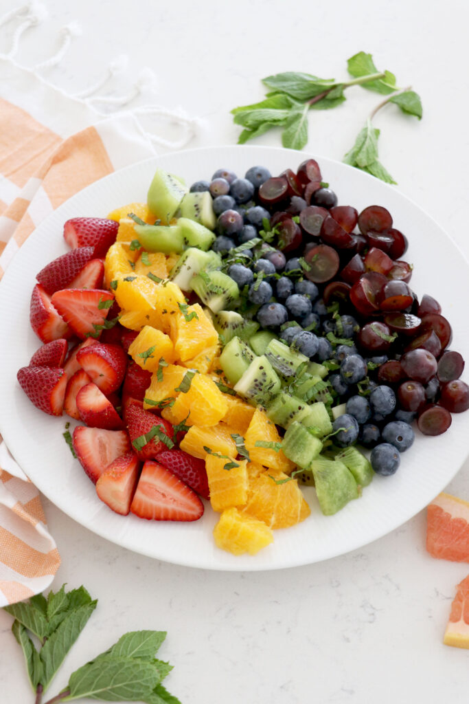 White plate with layered rainbow fruit.