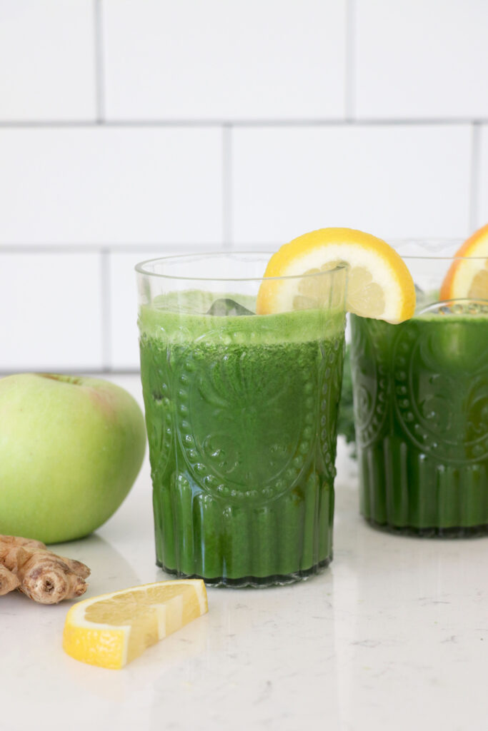 Green juice in glasses with fruit on the side.