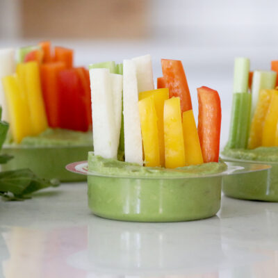 Individual cups of mashed avocado with sliced vegetables