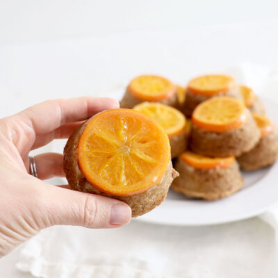 Hand holding individual orange cake with more in background