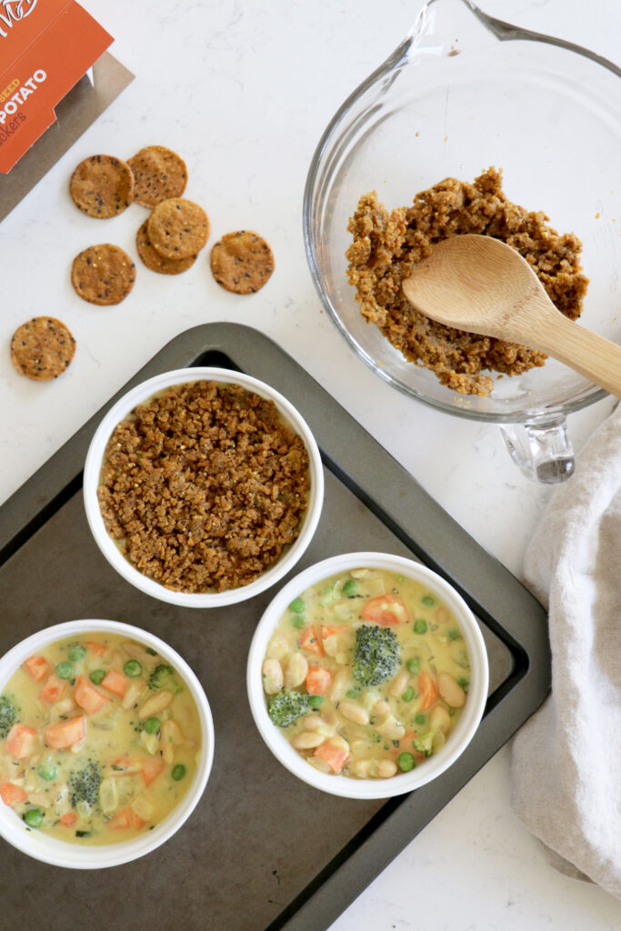 Three white ramekins with plant-based pot pie and a cracker crust.